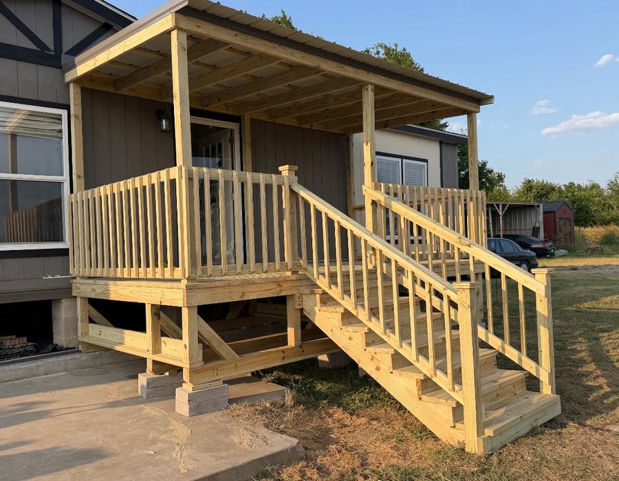 Portable covered deck with stairs beside a mobile home